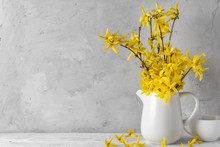 Womans Day Or Spring Concept. Still Life With Yellow Forsythia Flowers And Coffee Cup On Concrete Background