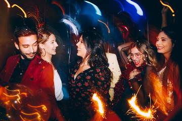 Group of friends having fun and holding sparklers at New Year's party