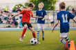 © matimix - Young boys playing soccer game. Training and football match between youth soccer teams. Junior competition between players running and kicking soccer ball. Final game of football tournament for kids