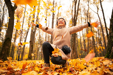 a young girl throws up autumn leaves