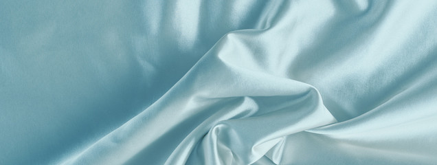 Light blue silk background with a folds.  Abstract texture of rippled satin surface, long banner