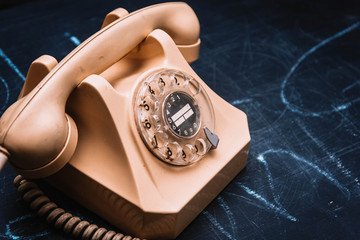 Beige retro telephone on a dark background.