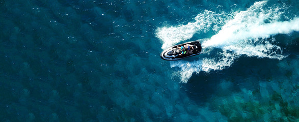 Wall Mural - Aerial drone ultra wide photo of jet ski watercraft cruising in high speed in deep blue open ocean sea