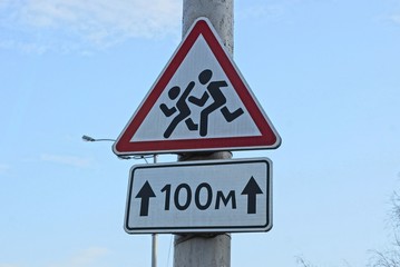 children road sign and arrow pointer hang on a concrete pillar in the street against a blue sky