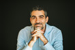 © annanahabed - Portrait of handsome man wearing blue shirt, leaning on hands, posing on black background