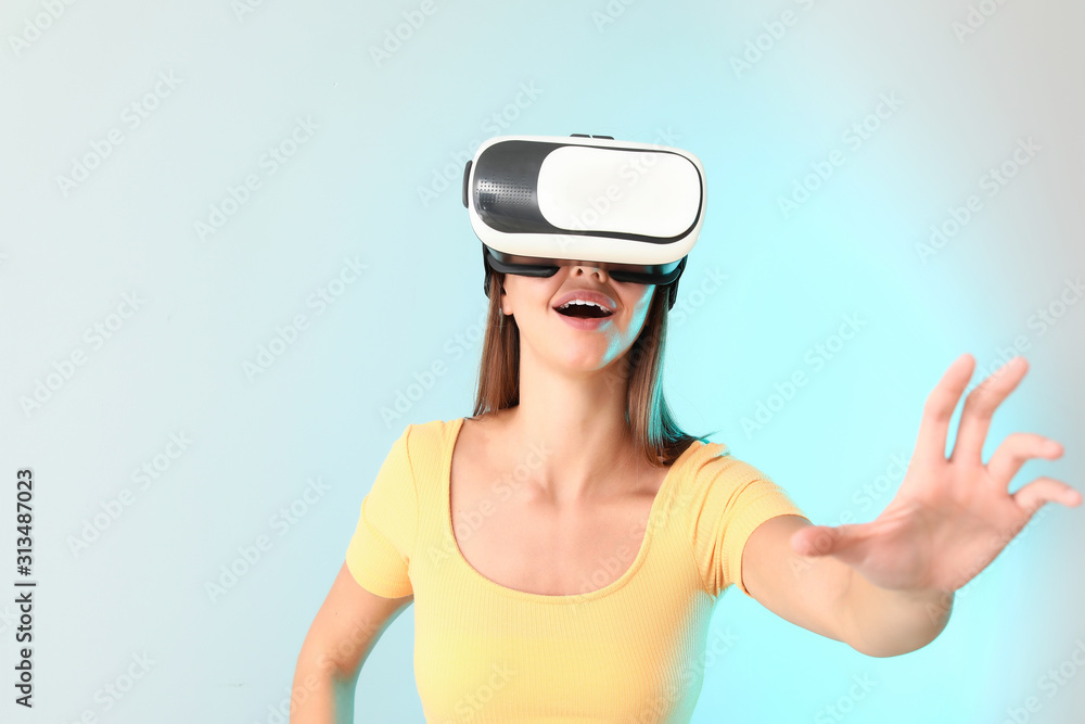 Young woman with virtual reality glasses on light background