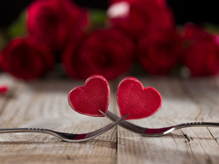 Two hearts between two forks on a table, close up