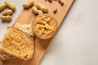 Board with fresh bread and tasty peanut butter on white background