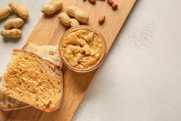 Wall Mural - Board with fresh bread and tasty peanut butter on white background