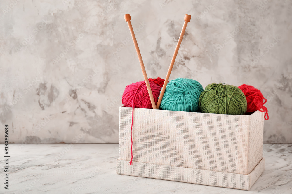 Knitting yarn with needles in box on light background