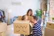 © Krakenimages.com - Beautiful famiily, kid playing with his parents riding cardboard fanny box at new home