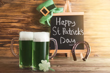 Mugs Of Green Beer For St. Patrick's Day On Wooden Table