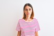 © Krakenimages.com - Beautiful redhead woman wearing casual striped pink t-shirt over isolated background with serious expression on face. Simple and natural looking at the camera.