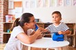 © Krakenimages.com - Beautiful teacher and toddler boy playing with vintage blue phone at kindergarten