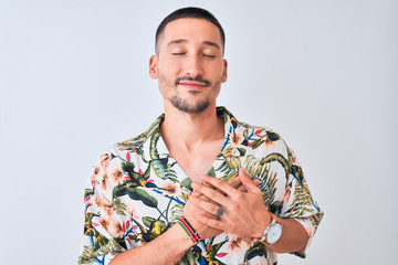 Sticker - Young handsome man wearing Hawaiian summer shirt over isolated background smiling with hands on chest with closed eyes and grateful gesture on face. Health concept.