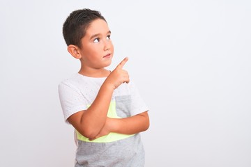 Poster - Beautiful kid boy wearing casual t-shirt standing over isolated white background with a big smile on face, pointing with hand and finger to the side looking at the camera.