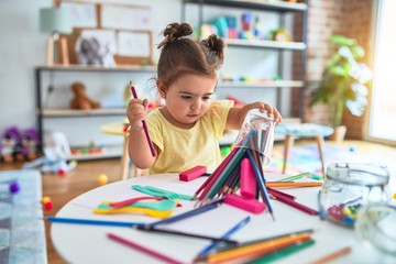 Beautiful toddler standing holding colored pencils at kindergarten