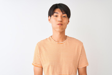 Wall Mural - Young chinese man wearing casual striped t-shirt standing over isolated white background puffing cheeks with funny face. Mouth inflated with air, crazy expression.