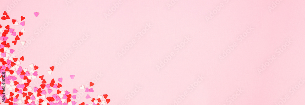 Valentines Day corner border banner with candy heart sprinkles over a pink textured background. Copy space. - obrazy, fototapety, plakaty 