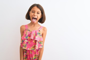 Poster - Young beautiful child girl wearing pink floral dress standing over isolated white background sticking tongue out happy with funny expression. Emotion concept.