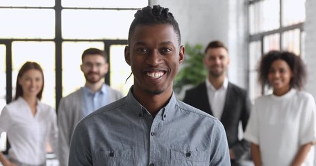 Wall Mural - Confident smiling millennial african businessman looking at camera in office