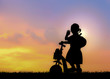 © showcake - Silhouette of little girl using a scooter in nature sunset