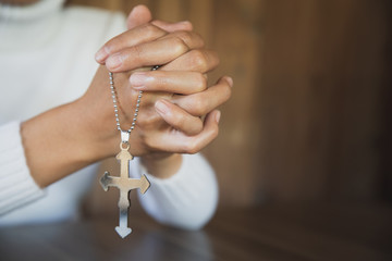 Wall Mural - A close-up shot of a woman with a cross and praying Pray or pray to God Concepts of religion, beliefs and people Begging for forgiveness and believing in goodness.