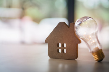 Wood house with Light bulb on the table, a symbol for construction, Creative light bulb idea, power energy or business idea concept ecology, loan, mortgage, property or home.