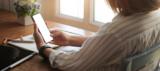 Cropped shot view of woman hands holding smart phone with blank copy space screen for your text message or information content, female reading text message on cell telephone during in urban setting. 