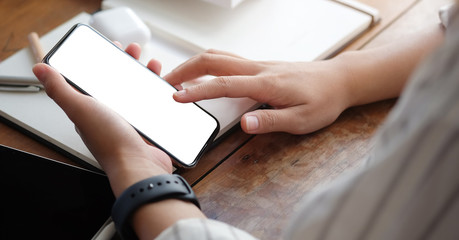 Cropped shot view of woman hands holding smart phone with blank copy space screen for your text message or information content, female reading text message on cell telephone during in urban setting. 