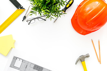 Builder work desk with hard hat, instruments and blueprints on white background top-down frame copy space