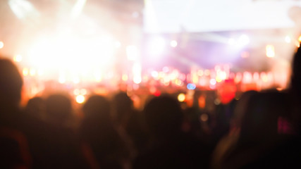 crowd at concert - summer music festival in front of bright stage lights. Dark background, smoke, concert spotlights.people dancing and having fun in summer festival