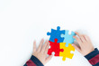 Top view, hands of an autistic child play colorful puzzle which is a symbol of public awareness for autism spectrum disorder - World Autism Awareness day on April 2, Understanding and Acceptance.