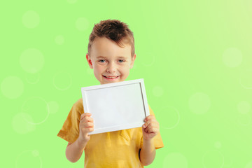 Happy child boy  holding a poster for your information on the blue background 