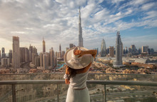 Woman With A White Hat Is Standing On A Balcony In Front Of The Skyline From Dubai Downtown