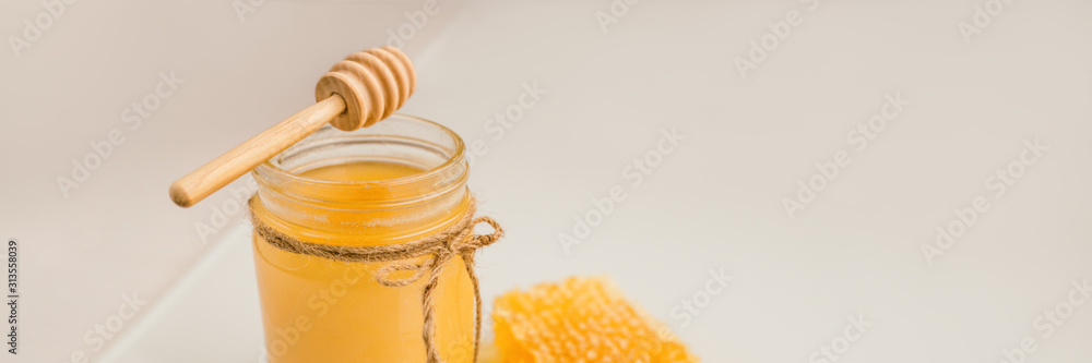 Honey pot with honey dipper and natural honeycomb banner background. - obrazy, fototapety, plakaty 