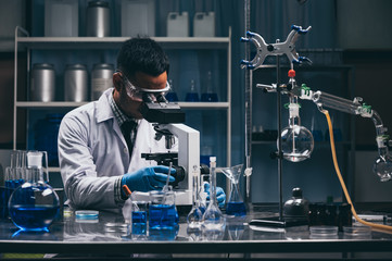 Wall Mural - young scientist looking through a microscope in a laboratory. young scientist doing some research.