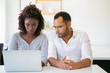© Mangostar - Focused employees using laptop while sitting at office. African American woman typing on laptop. Teamwork concept
