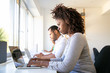 © Mangostar - Focused young woman using laptop. Closeup shot of thoughtful African American worker sitting at table with laptop. Technology concept