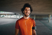 Cheerful Portrait Of A Healthy Sporty Young Man Enjoying Listening To Music On Earphones Standing On City Street