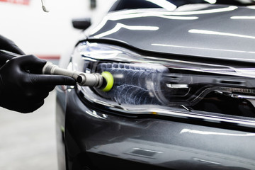 Car detailing - Worker with orbital polisher in auto repair shop.