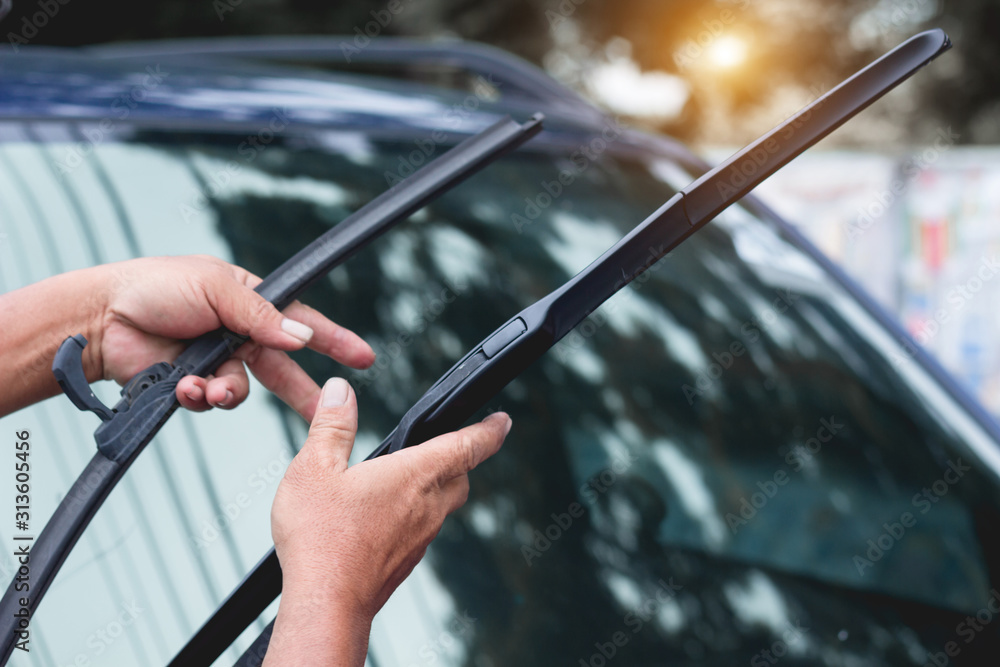 Mechanic replace windshield wipers on car. Replacing wiper blades - obrazy, fototapety, plakaty 