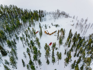 Aerial view of wooden log cabin or cottage in snow  winter forest by the lake in rural Finland Lapland