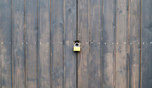 Wooden Surface Of Old Textured Brown Planks Closed On A Rusted Lock Close Up. Old Wooden Gate With A Metal Lock. Brown Wooden Door With A Lock