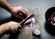 © Simon Bajada - Overhead view of man's hands cutting onion on cutting board