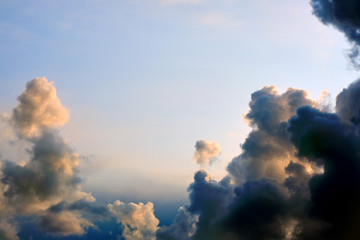 Wall Mural - Black thundercloud sunset divides the sky in half. Beautiful clouds in the rays of sunlight, copy space. Dark storm clouds leave the clear blue sky in warm summer weather, cleared up.