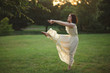 © Cavan Images - A young woman dances barefoot in a tree-lined park at sunset