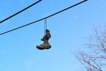 Pair Of Boots Hanging On Power Line With Blue Sky