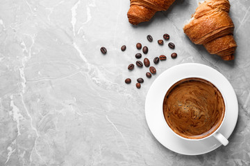 Tasty fresh croissants and coffee on light grey marble table, flat lay. Space for text