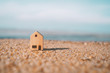 © tonktiti - Small home model on sunset beach sand texture background.